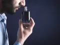 Mężczyzna wącha perfumy z buteleczki.