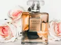 Flakon perfum Chanel Coco Mademoiselle otoczony różowymi różami.