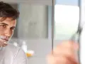 Mężczyzna goli twarz pianką do golenia, trzymając maszynkę.