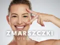 Uśmiechnięta kobieta z widocznymi zmarszczkami mimicznymi na czole i wokół oczu. Dłoń dotyka jej twarzy.