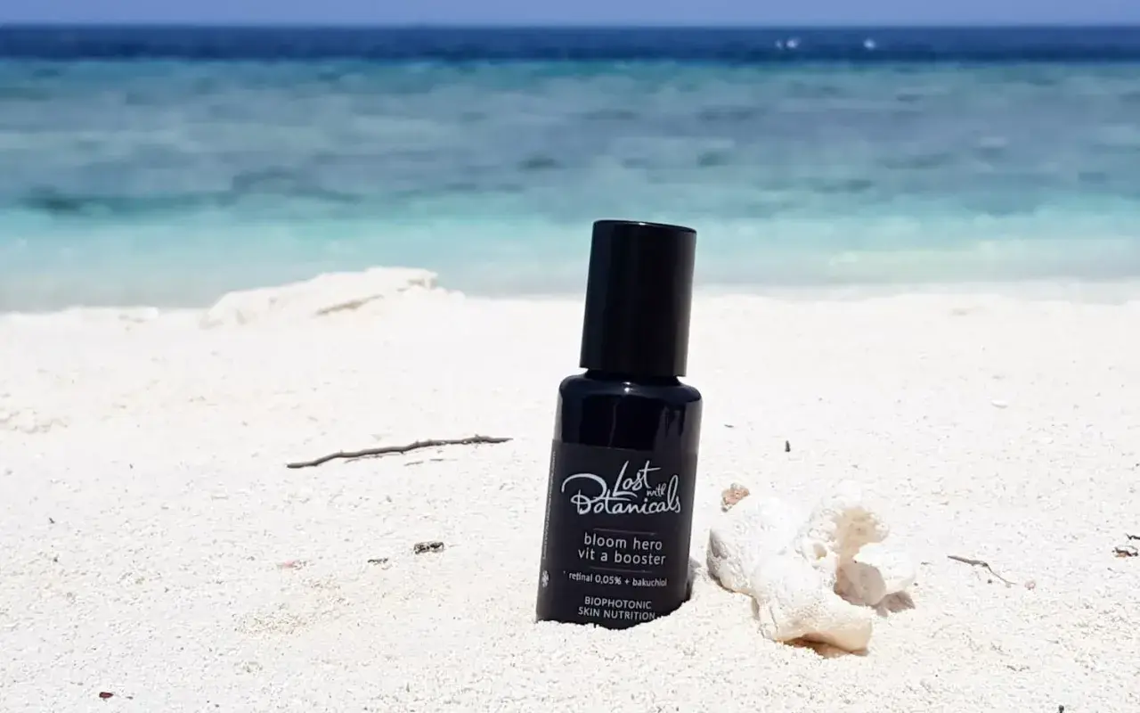 Czarny flakonik z kosmetykiem na plaży. Zawiera retinoidy bez recepty, idealny na wakacje.