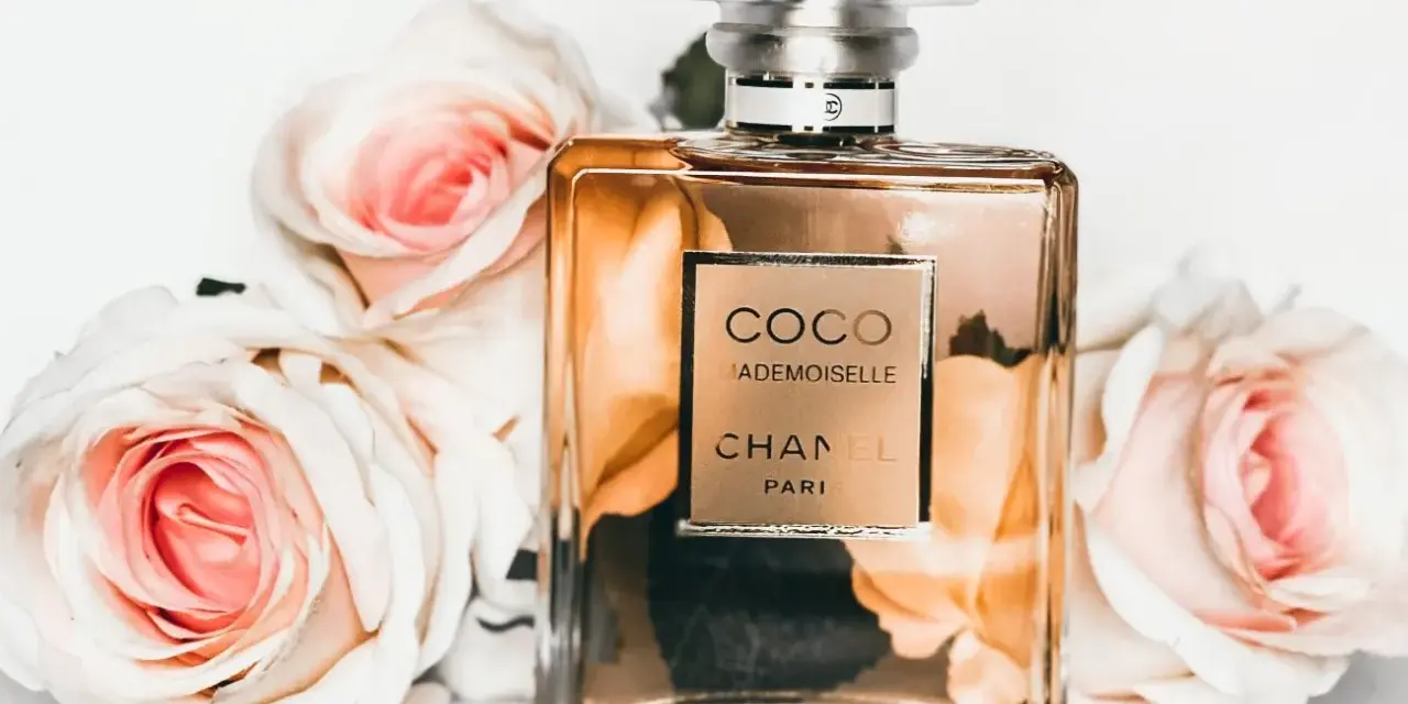 Flakon perfum Chanel Coco Mademoiselle otoczony różowymi różami.