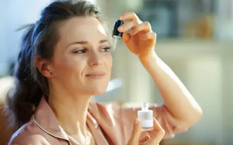 Kobieta aplikuje serum z **retinalem** na skórę pod okiem, dbając o młody wygląd.