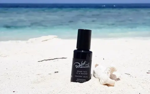 Czarny flakonik z kosmetykiem na plaży. Zawiera retinoidy bez recepty, idealny na wakacje.