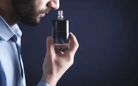 Mężczyzna wącha perfumy z buteleczki.