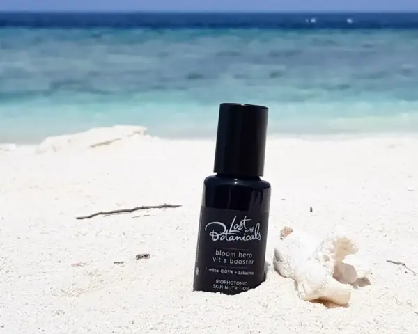 Czarny flakonik z kosmetykiem na plaży. Zawiera retinoidy bez recepty, idealny na wakacje.