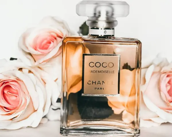 Flakon perfum Chanel Coco Mademoiselle otoczony różowymi różami.