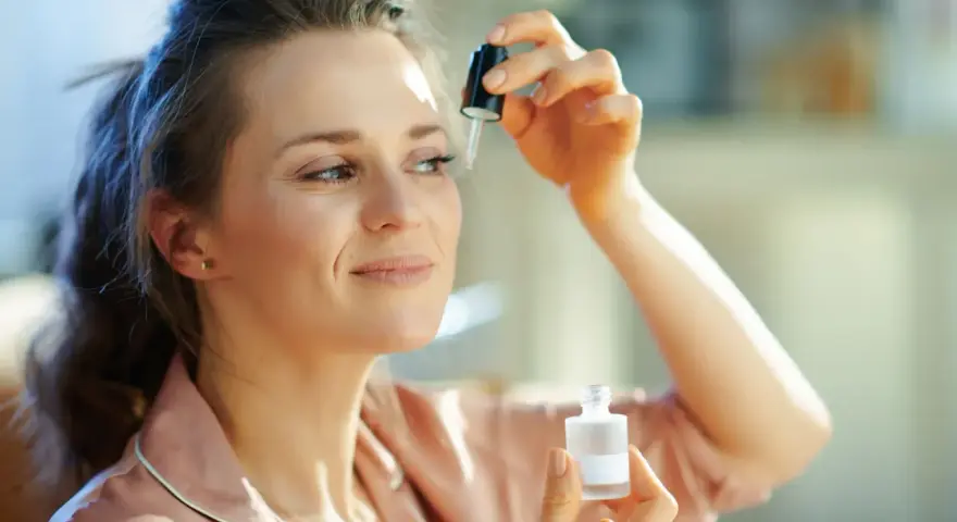 Kobieta aplikuje serum z **retinalem** na skórę pod okiem, dbając o młody wygląd.