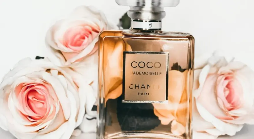 Flakon perfum Chanel Coco Mademoiselle otoczony różowymi różami.