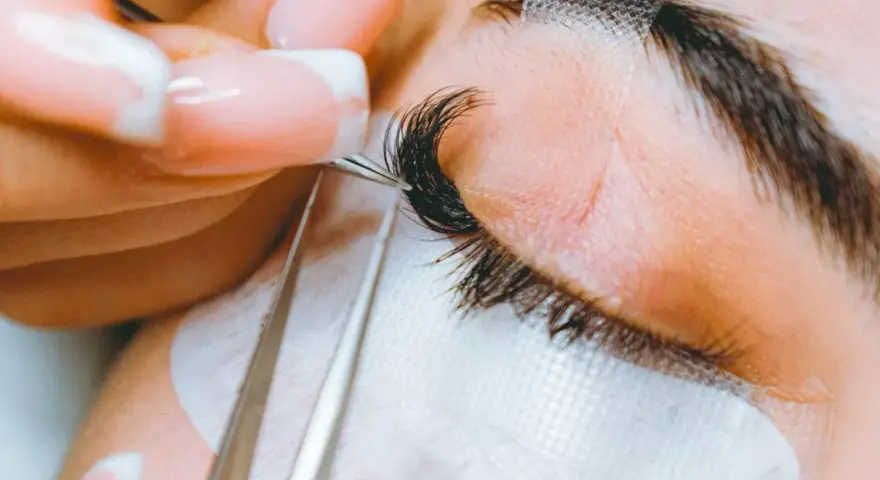 Precyzyjne przedłużanie rzęs: porównanie rzęsy 2d i 3d. Stylistka z perfekcyjnym manicurem dokłada kępki.